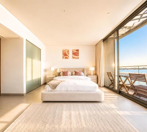 a bedroom with a large bed and a balcony at Ajmal Villa in Al Ḩamrīyah