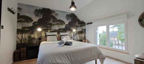a bedroom with a bed with a painting on the wall at Le Jardin des 2 Cèdres in Isigny-le-Buat