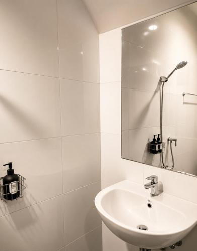 a white bathroom with a sink and a mirror at Nasrina's House Hat Yai ใกล้เซ็นทรัลหาดใหญ่ in Sathani Khlong Rian