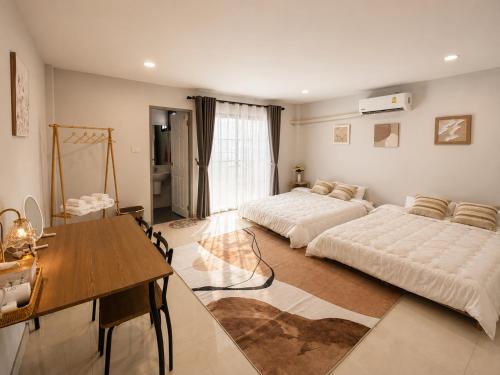 a bedroom with two beds and a table and a dining room at Nasrina's House Hat Yai ใกล้เซ็นทรัลหาดใหญ่ in Sathani Khlong Rian