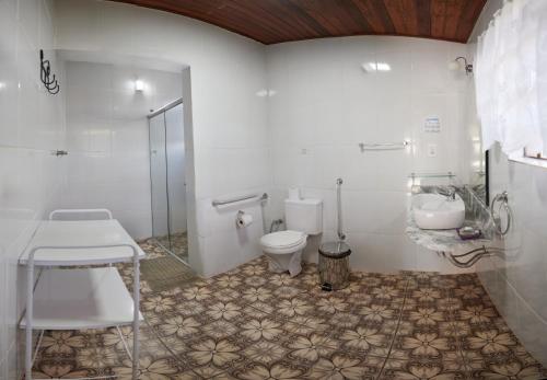 a bathroom with a toilet and a sink at Pousada Capão da Coruja in Santa Bárbara