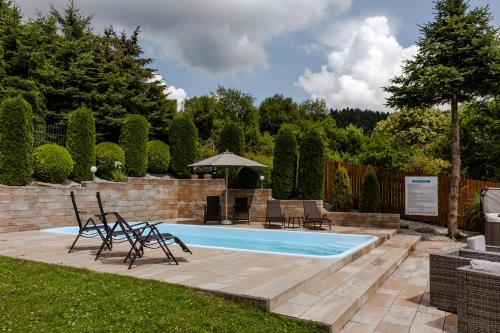 a swimming pool in a yard with chairs and a table at Willa Karla in Krynica Zdrój