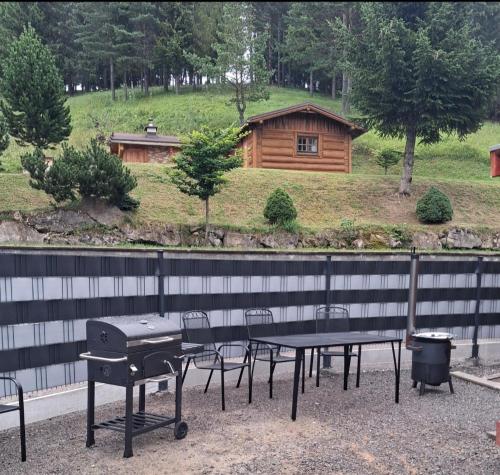 a picnic table and grill with a house in the background at Chata Borovec in Veľké Borové