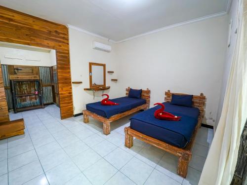 a room with two blue beds and a mirror at Sunrise Lodge & Lounge in Singaraja