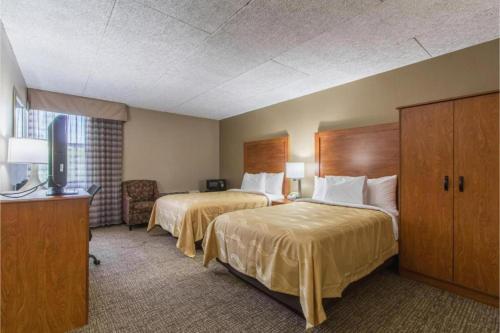 a hotel room with two beds and a television at GreenRidge Hotel in Wickliffe
