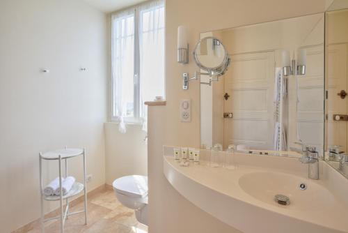 a bathroom with a sink and a toilet and a mirror at Hôtel Restaurant De La Poste & Du Lion D'or in Vézelay