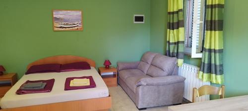 a bedroom with a bed and a couch and a chair at Apartmani Volme in Banjole