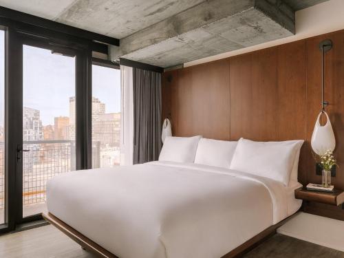 a large white bed in a room with a large window at Merchant LES Hotel in New York