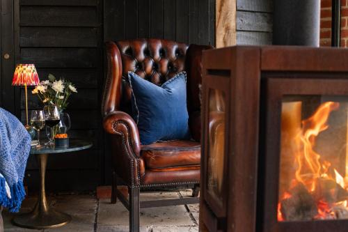 a leather chair with a blue pillow next to a fireplace at The Pear Tree Inn in Bury Saint Edmunds