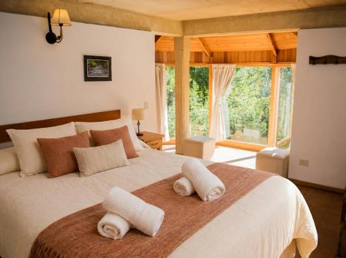 a bedroom with a large bed with towels on it at Cabañas Rucaleufu in San Martín de los Andes