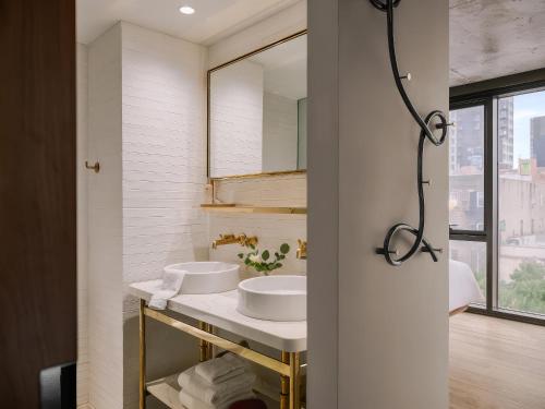 a bathroom with two sinks and a mirror at Merchant LES Hotel in New York