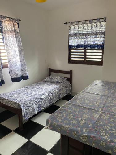 a room with two beds and a table and windows at Apartamento in Natal