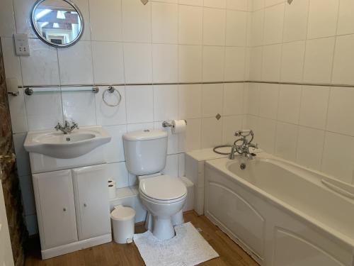 a bathroom with a toilet and a sink and a tub at The Hayloft in Wigton