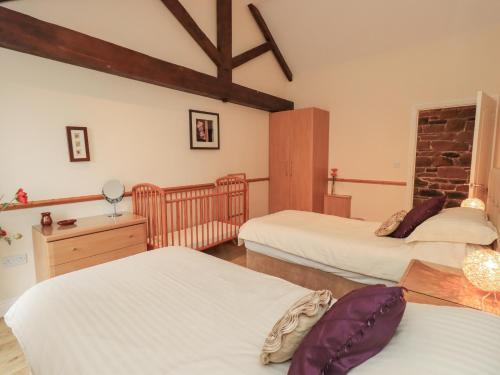 a bedroom with three beds and a dresser in it at The Hayloft in Wigton