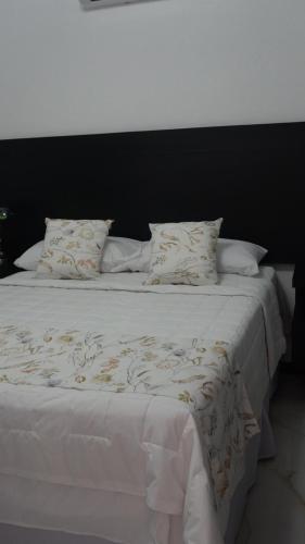 a large white bed with white sheets and pillows at Hotel Makao in La Rosita