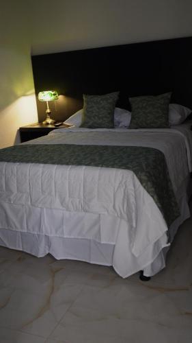 a bedroom with a large white bed and a lamp at Hotel Makao in La Rosita