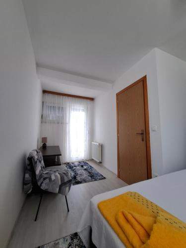 a bedroom with a bed and a chair and a window at Apartman Mostar in Mostar