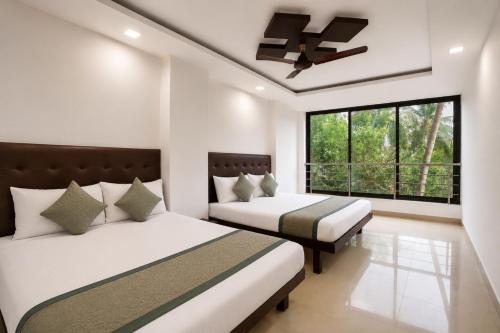 a bedroom with two beds and a ceiling fan at Hotel Sawaastic in Calangute North GOA in Calangute