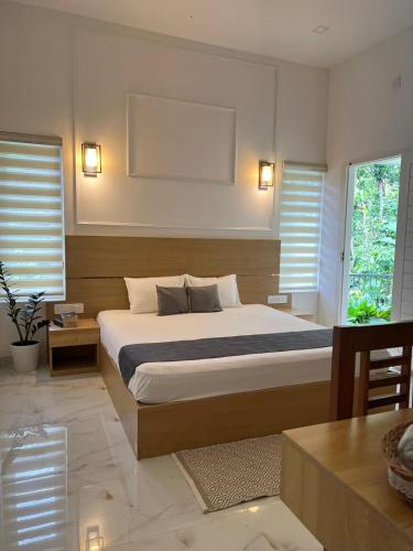 a bedroom with a large bed and two windows at Trinity Villa Home Stay in Idukki
