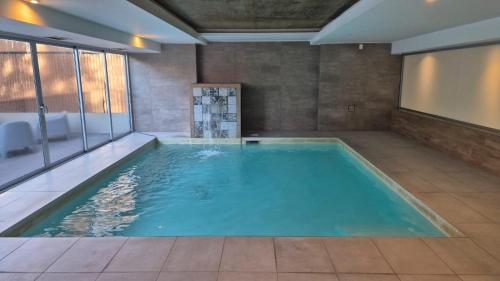 a large swimming pool with blue water in a room at Gran Hotel Dakar in Mendoza