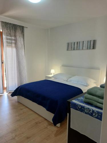 a bedroom with a large bed with a blue blanket at Apartment Park in Rabac