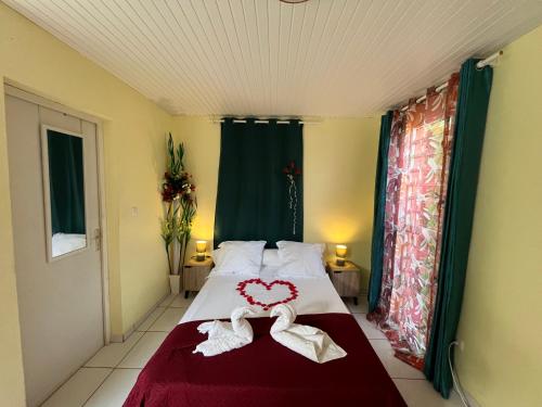a bedroom with a bed with two hearts on it at Le Touloulou , vue mer et jardin tropical in Le Lorrain