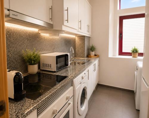 a kitchen with a sink and a microwave at Casa das Amas do Cardeal in Évora