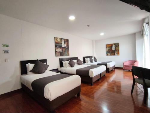 a hotel room with three beds and a chair at Hotel macao colombia in Bogotá