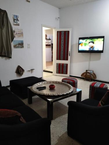 a living room with a table and a flat screen tv at Relax in Tunis