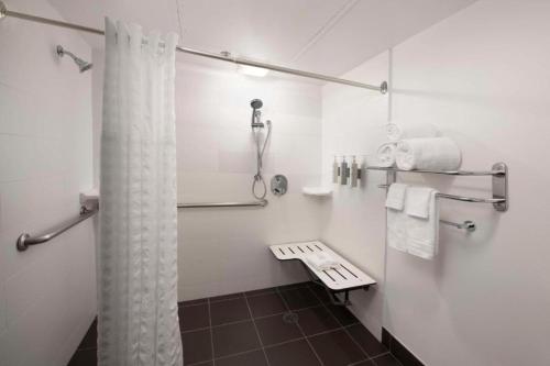 a bathroom with a shower and a bench and towels at The Signature Suites in Irving
