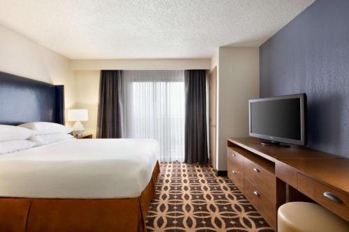 a hotel room with a bed and a flat screen tv at The Signature Suites in Irving
