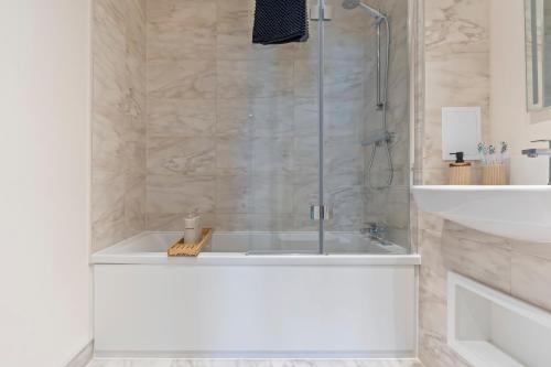 a bathroom with a shower and a tub and a sink at 2 Bed Flat, Pool Table, Terrace 4 stops to Wembley in Hatch End