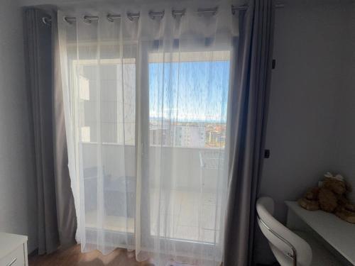 a window with white curtains and a teddy bear at REA Apartment in Shkodër