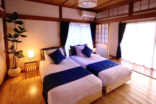 two beds in a room with two windows at Zen House - Tajimi in Tajimi