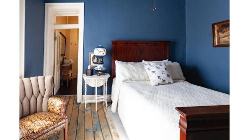 a bedroom with blue walls and a bed and a chair at Annie Oakley in Cimarron