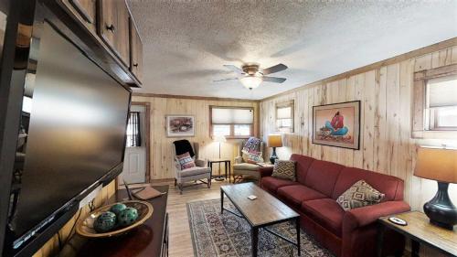 a living room with a red couch and a black refrigerator at Knotty & Nice in Red River