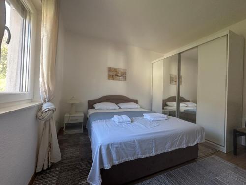 a bedroom with a bed with white sheets and a mirror at Villa Ramea in Kovačevo Polje
