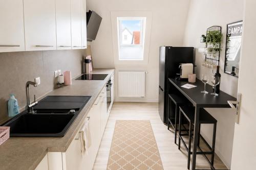 a kitchen with black counter tops and a black refrigerator at SCHEE Panorama Apartment - ideal für Gruppen und Familien in Nördlingen