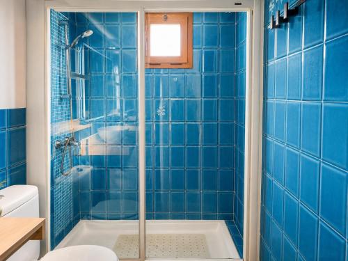 a blue tiled bathroom with a shower and a tub at Formenterasuite 16 in Es Pujols