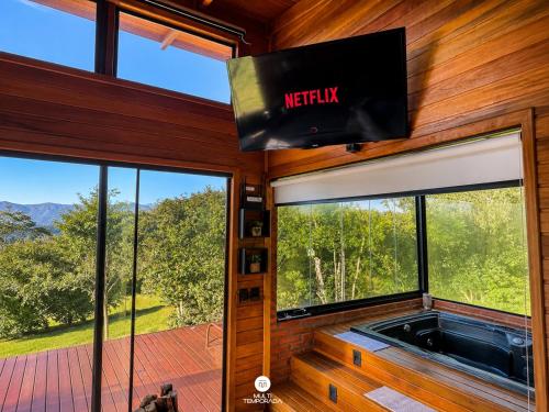 a view of a tv in a room with windows at Cabana Bad Wolf - Rancho Queimado - SC in Rancho Queimado