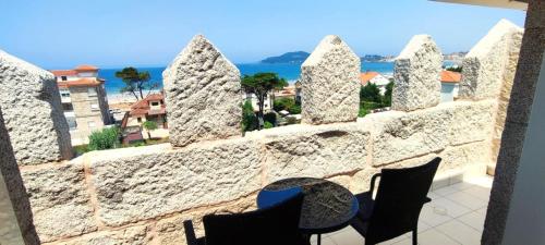 a stone wall with chairs and a view of the ocean at Hotel Miramar Playa America Nigran in Nigrán