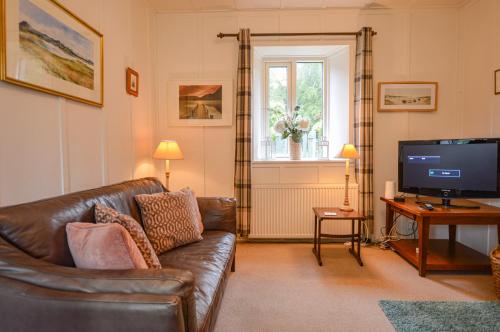 a living room with a leather couch and a television at Darroch Beag in Saint Catherines