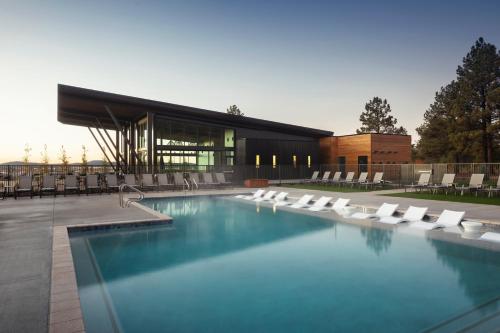 a swimming pool with white chairs and a building at Village Camp Flagstaff in Bellemont