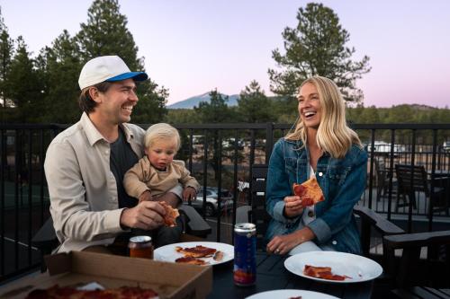 a man and a woman and a baby eating pizza at Village Camp Flagstaff in Bellemont