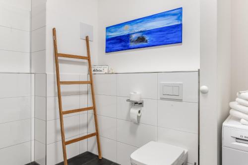 a bathroom with a toilet and a painting on the wall at Ferienwohnung Urlaubsglück- lichtdurchflutete Wohnung mit Balkon und Seesicht in Lindau