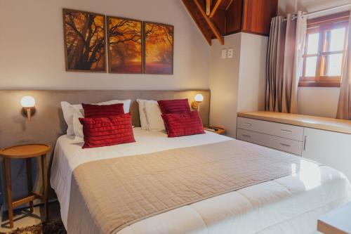 a bedroom with a large bed with red pillows at Cabanas Belo Destino in Gramado
