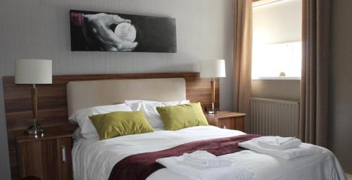 a bedroom with a bed with white sheets and green pillows at The Fairways Pub in Templebrough