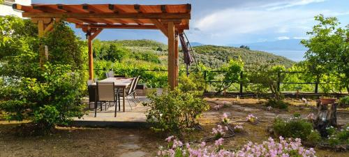 a pergola with a table and chairs in a garden at Mikros Paradisos Pelion in Áyios Vlásios