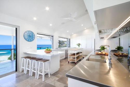 a kitchen with white counters and a view of the ocean at Ocean Panorama With Private Pool! in Noosa Heads