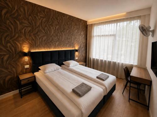 a bedroom with a large bed and a desk and a window at Hotel Holland Lodge in Utrecht